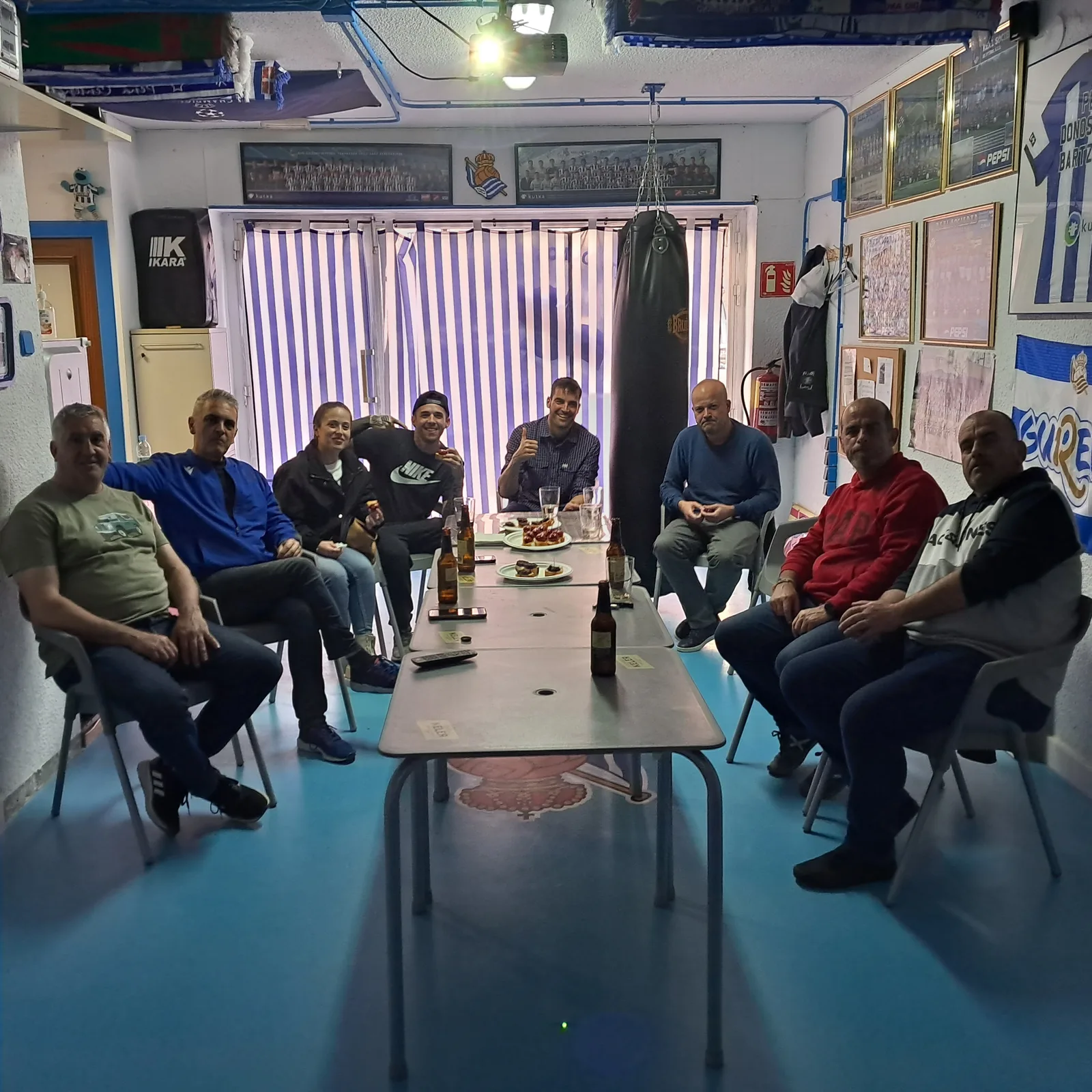 Socios de la peña reunidos en su local con banderas y fotos de equipo en las paredes