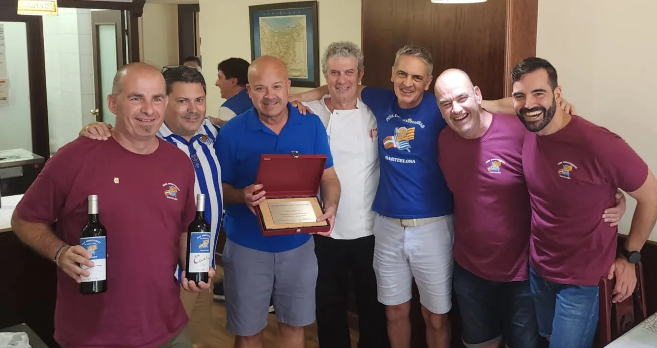 Socios posando con botellas de vino de la peña en un restaurante durante el 10º aniversario