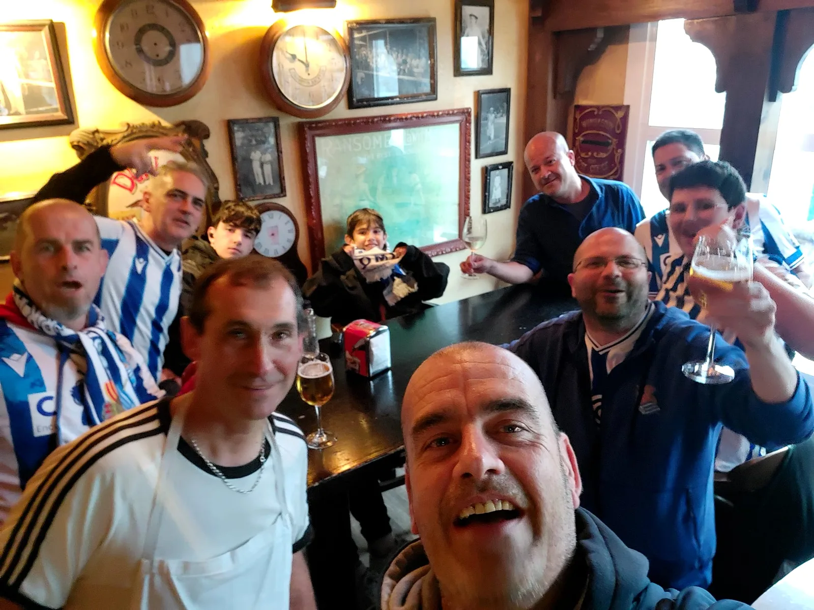 Socios de la peña brindando con cerveza y vino en el interior de un bar histórico de Donostia