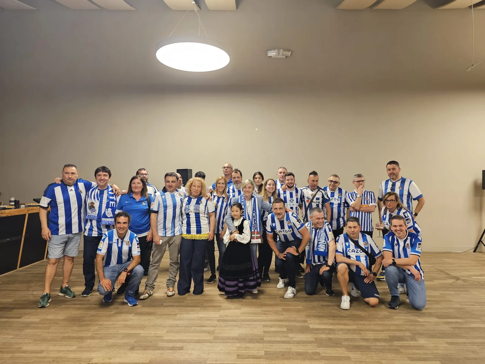 Socios abrazándose en el escenario durante el acto del aniversario de la Peña Galicia Txuri Urdin