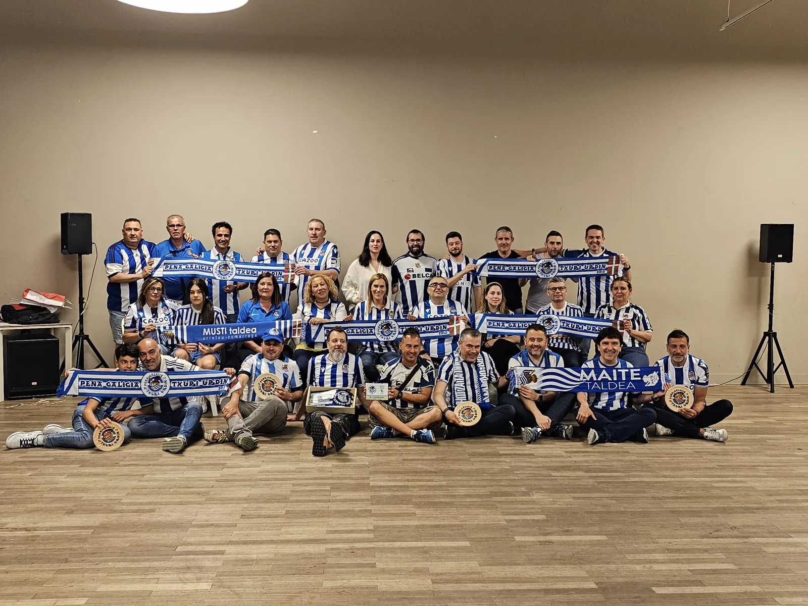 Foto de familia completa del acto de hermanamiento con la Peña Galicia Txuri Urdin, con bufandas desplegadas