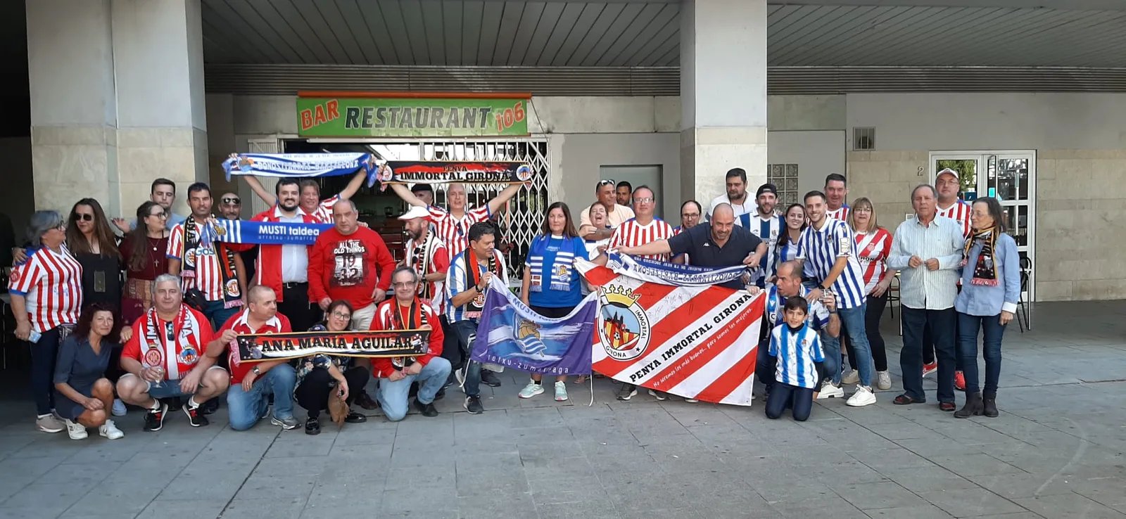 Socios de la Peña Donostiarras Bartzelona junto a la Penya Immortal Girona ante un bar de Girona