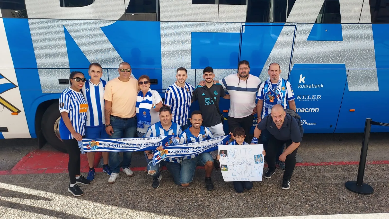 Socios de la peña con bufandas ante el autobús oficial de la Real Sociedad en Girona