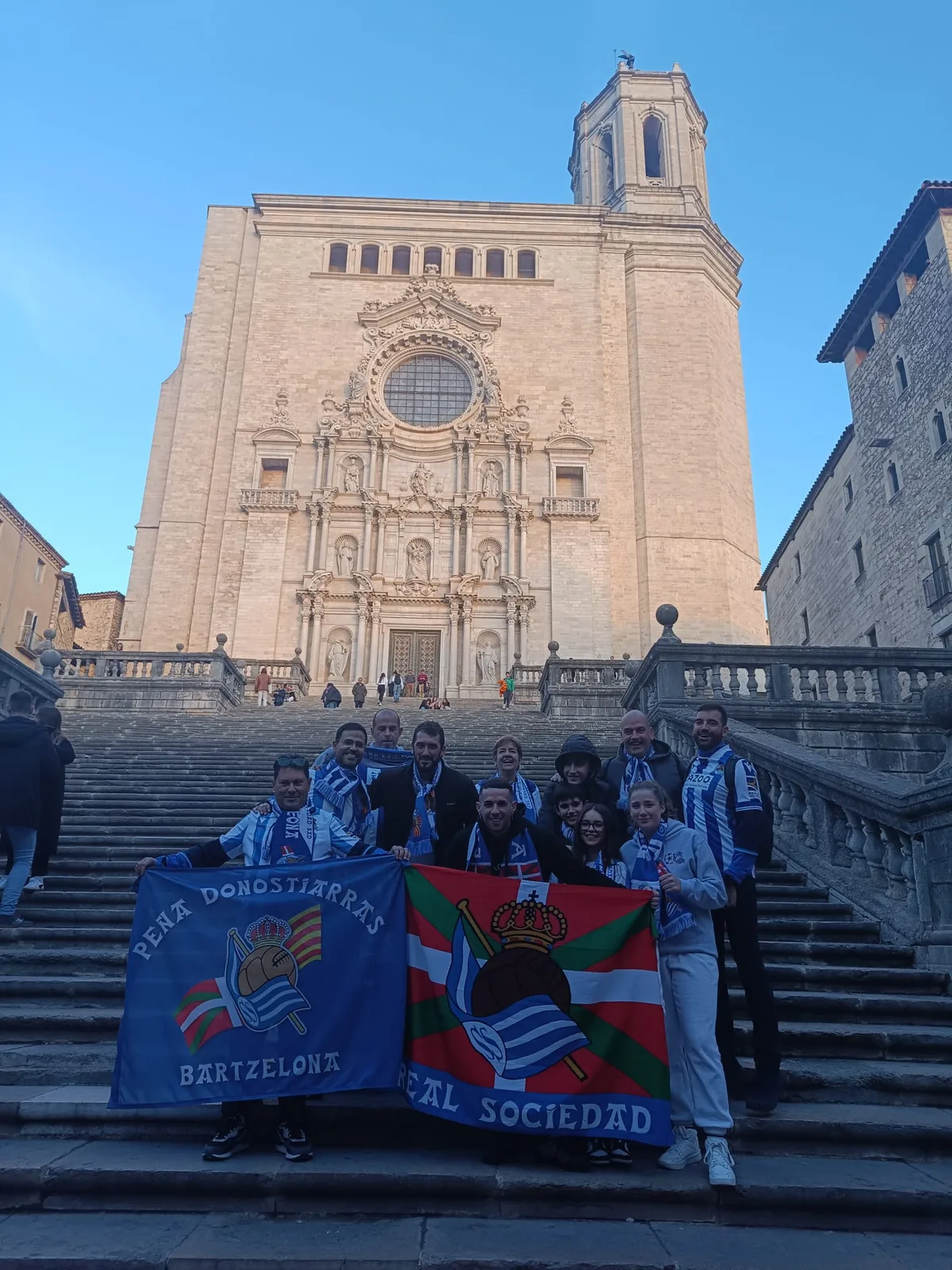 Socios con las banderas de la peña y de la Real Sociedad en la escalinata de la Catedral de Girona