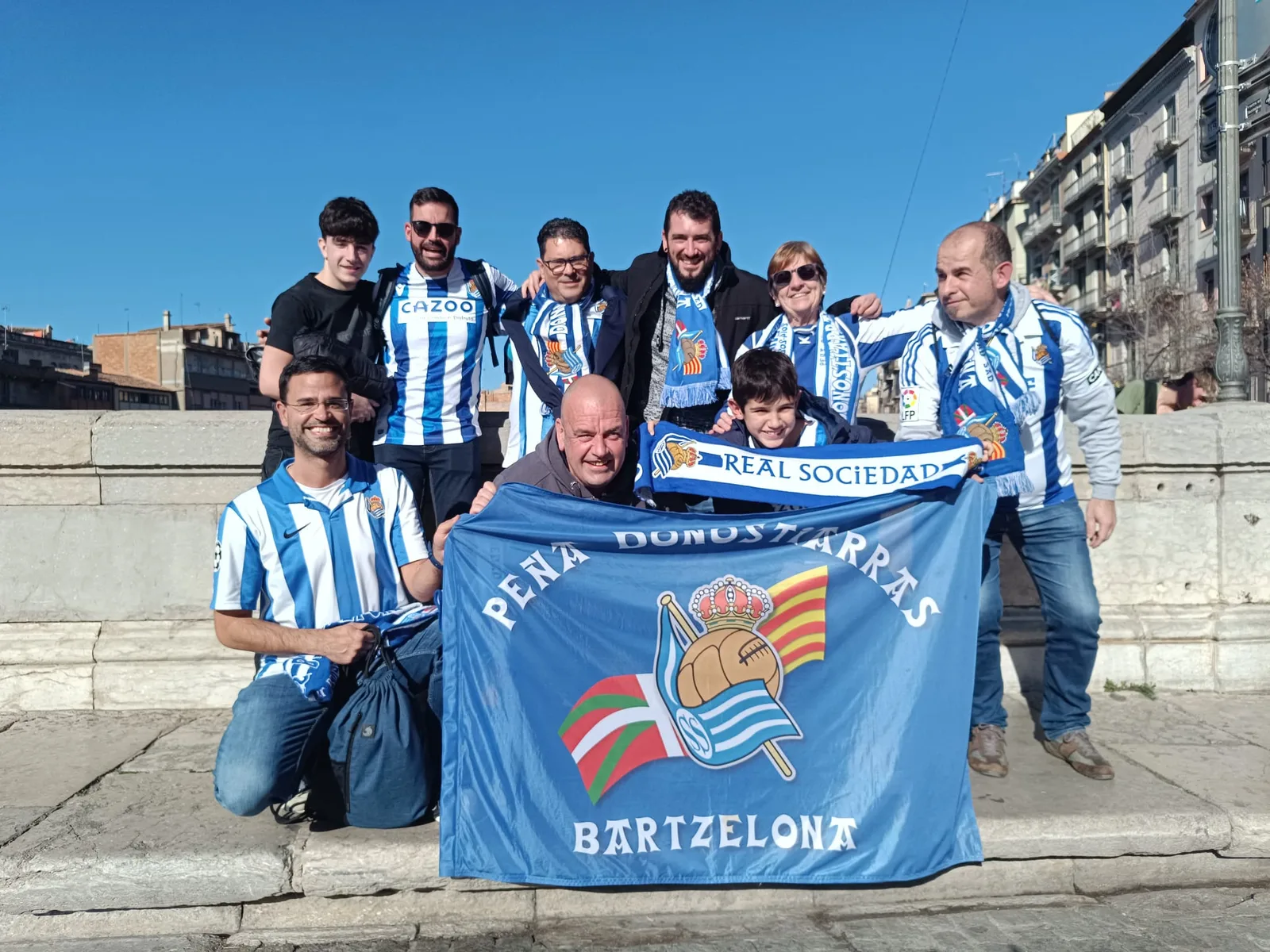 Socios con la bandera de la peña y una bufanda de la Real Sociedad en el puente sobre el Onyar en Girona