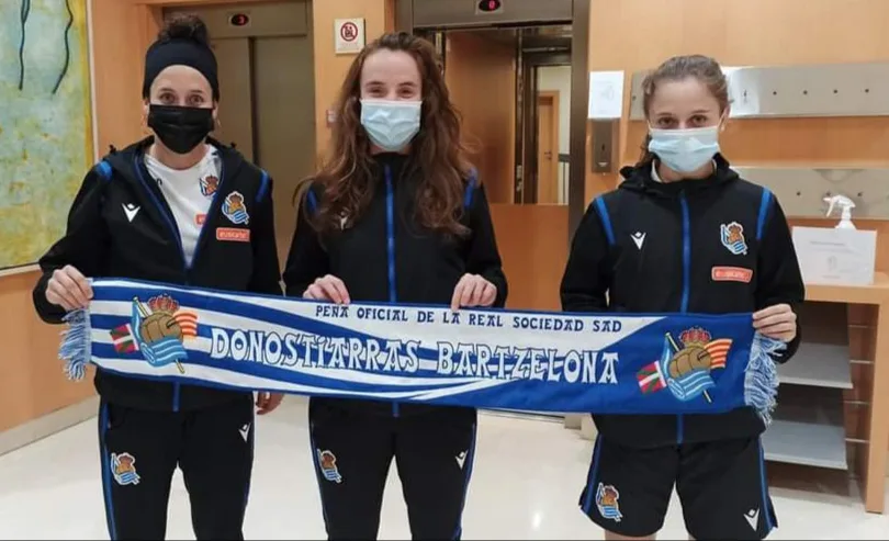 Tres jugadoras de la Real Sociedad femenina sujetando la bufanda de la Peña Donostiarras Bartzelona