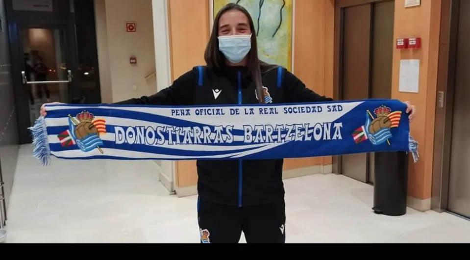 Jugadora de la Real Sociedad femenina sujetando la bufanda de la Peña Donostiarras Bartzelona en un hotel