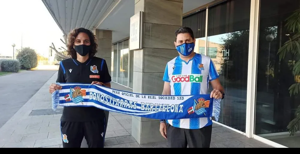 Jugadora de la Real Sociedad femenina y socio de la peña sujetando la bufanda en el exterior de un hotel