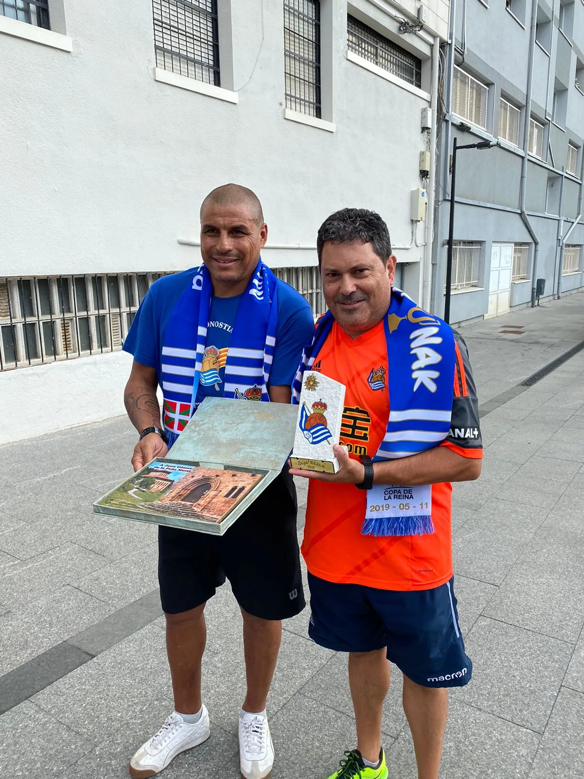 Juan Gómez y un socio de la peña sujetando una placa conmemorativa y un trofeo de recuerdo con la ikurriña