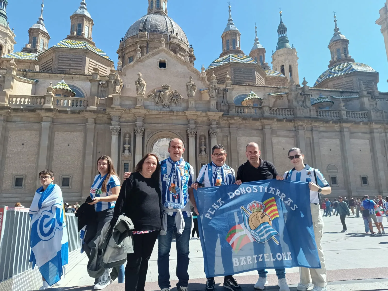Socios con la bandera de la peña ante la fachada de la Basílica del Pilar de Zaragoza
