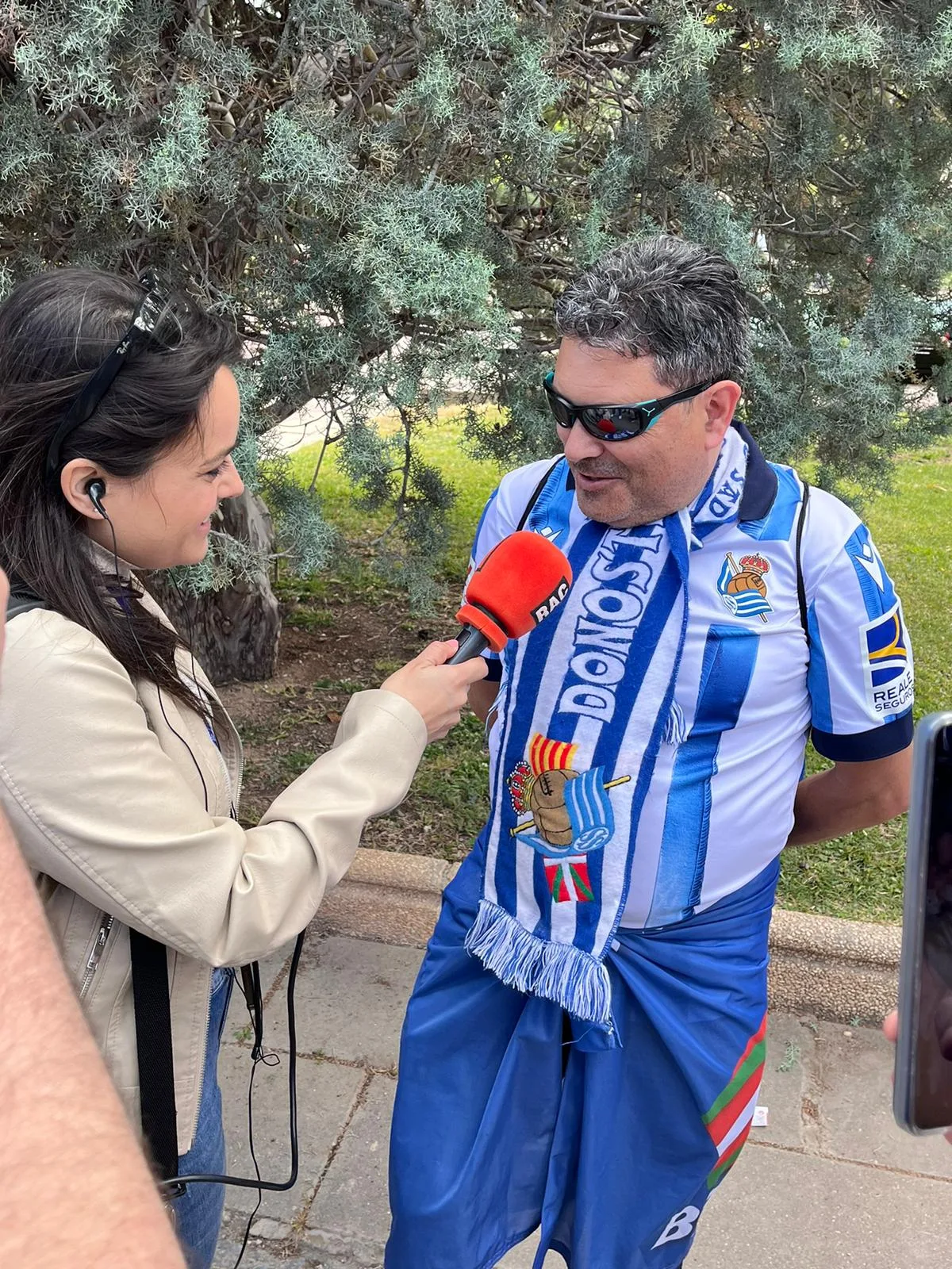 Socio con bufanda de la peña siendo entrevistado por una periodista de radio en Zaragoza