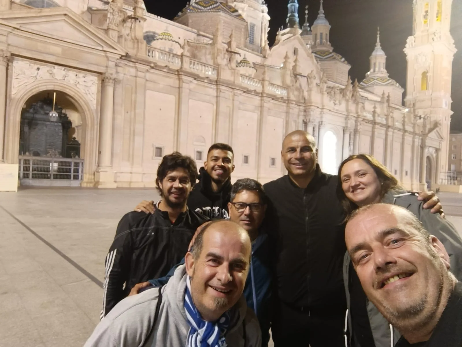 Socios de la peña de noche ante la Basílica del Pilar iluminada en Zaragoza