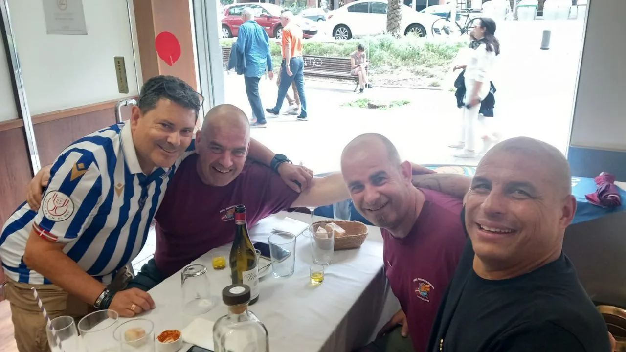Grupo de socios de la Peña Donostiarras Bartzelona en el local con camisetas de la Real Sociedad